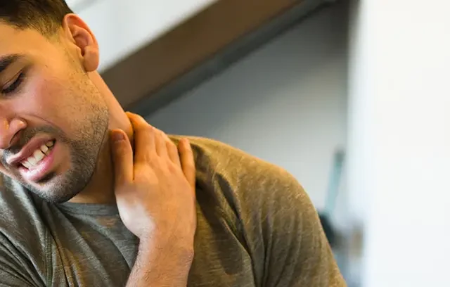 Hispanic sportsman suffering neck muscle tension following strenuous gym training, showing signs of physical strain and potential injury